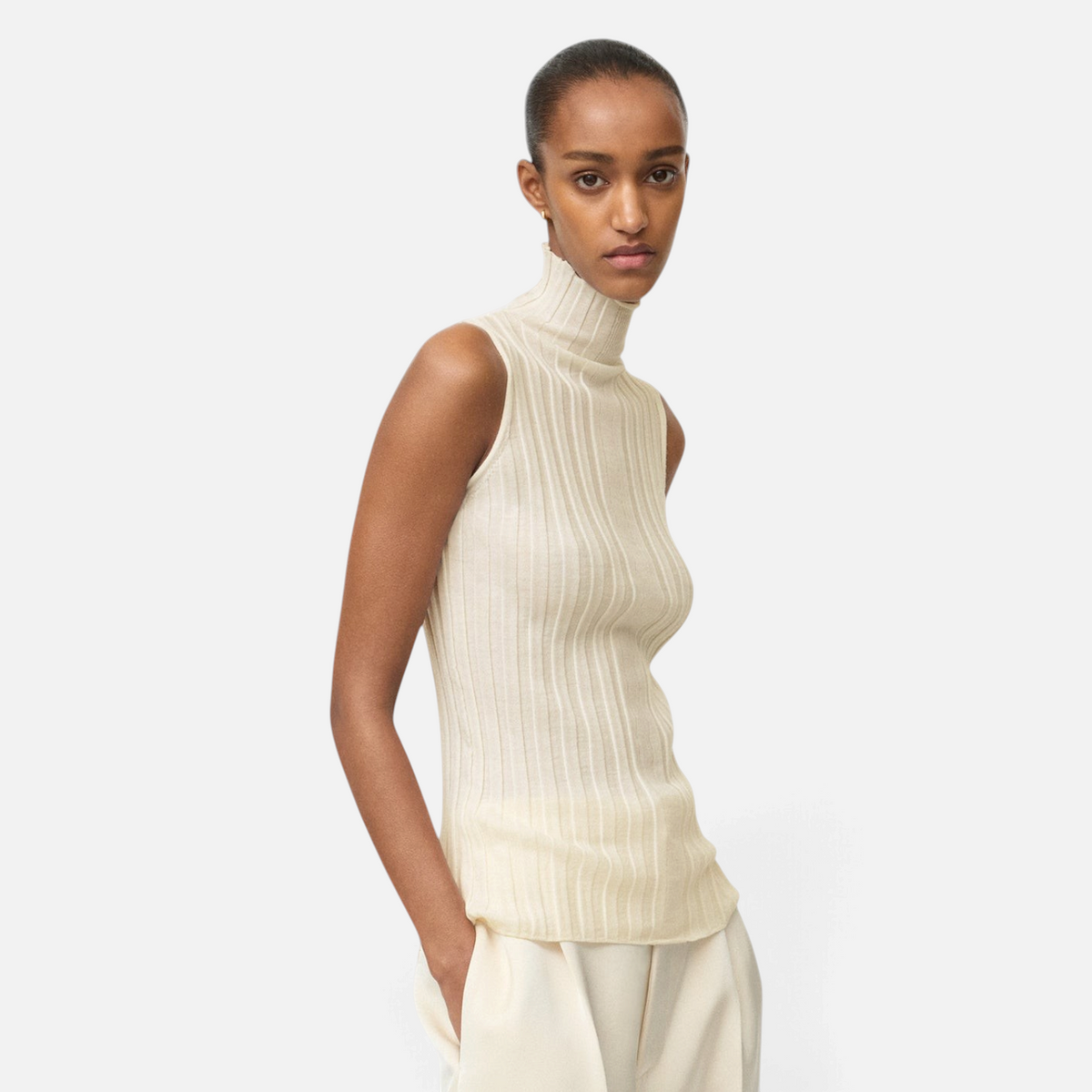 Shop Rescue Spa featherlight ribbed wool turtleneck singlet in cream worn by a model with wide-leg trousers