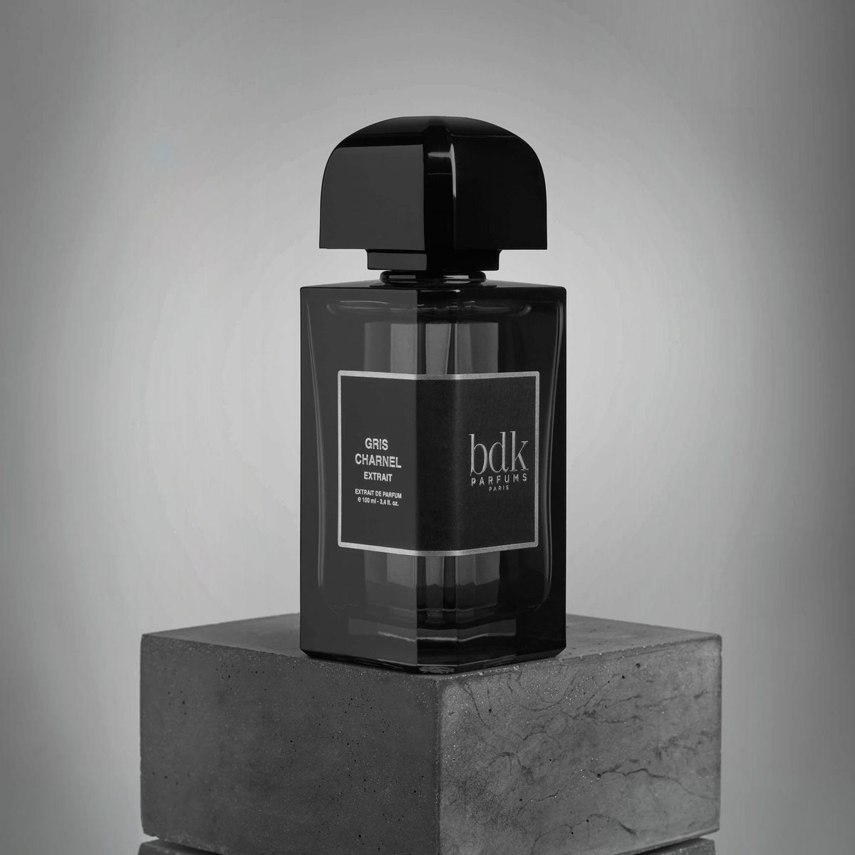Shop Rescue Spa Gris Charnel Extrait perfume bottle in black glass on a stone pedestal against a grey background.