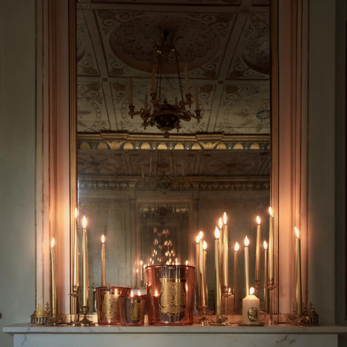 Shop Rescue Spa Nazareth holiday candle collection with copper mirror-effect glass on a mantelpiece with lit tapers.