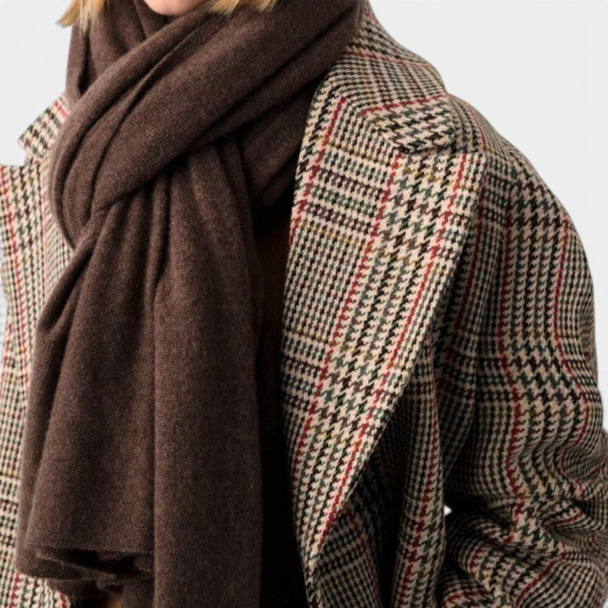 Shop Rescue Spa dark brown cashmere travel wrap worn over a plaid wool coat by a blonde model.