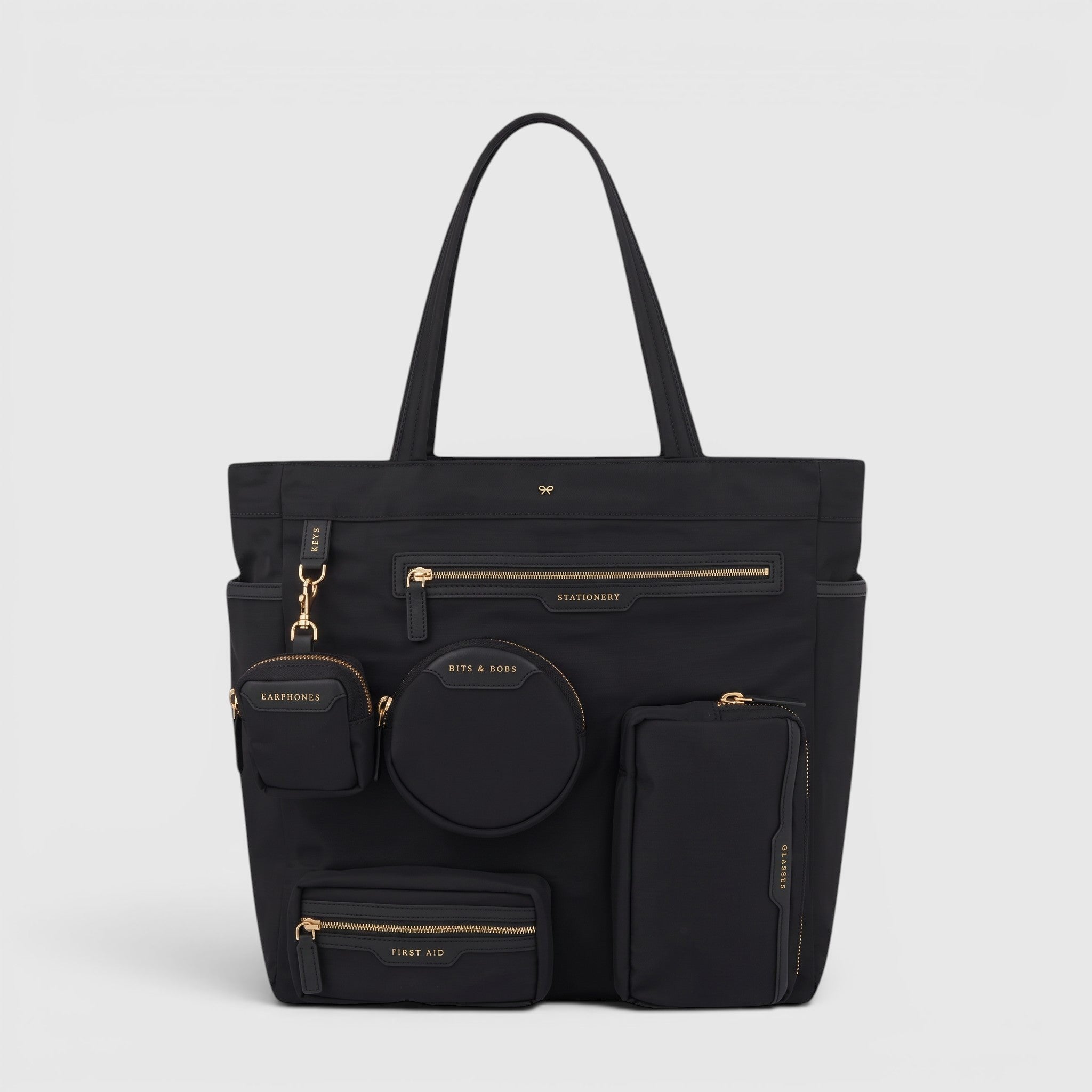 Shop Rescue Spa Anya Hindmarch black recycled nylon commuter tote with multiple external zip pockets and gold hardware
