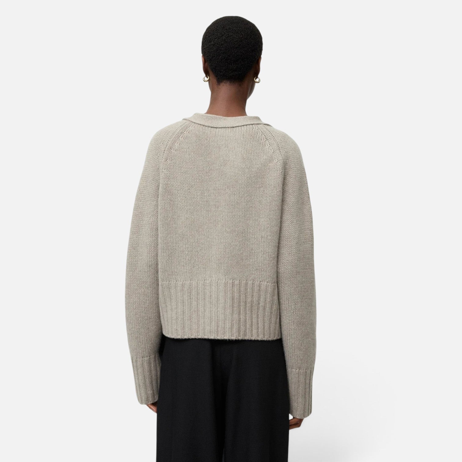 Back view of a model wearing a Shop Rescue Spa chunky knit beige cashmere cardigan with a relaxed fit