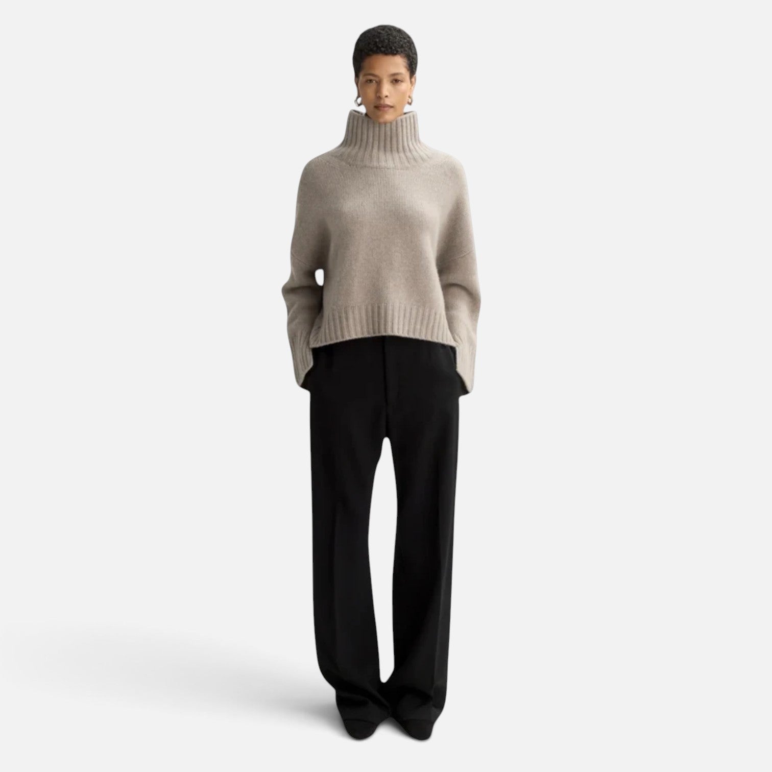 Model wearing a Shop Rescue Spa beige chunky cashmere turtleneck sweater with sleeve slits and a relaxed fit.