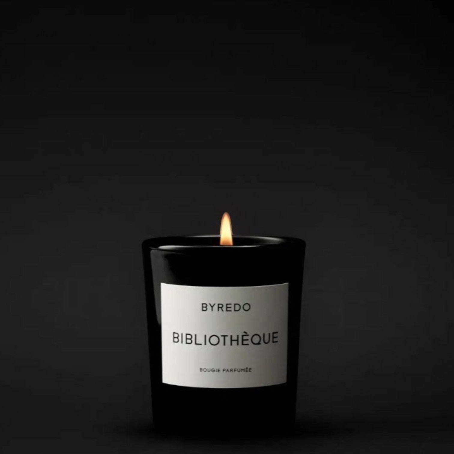 Shop Rescue Spa Bibliotheque scented candle in a black glass jar with a white label, lit flame.
