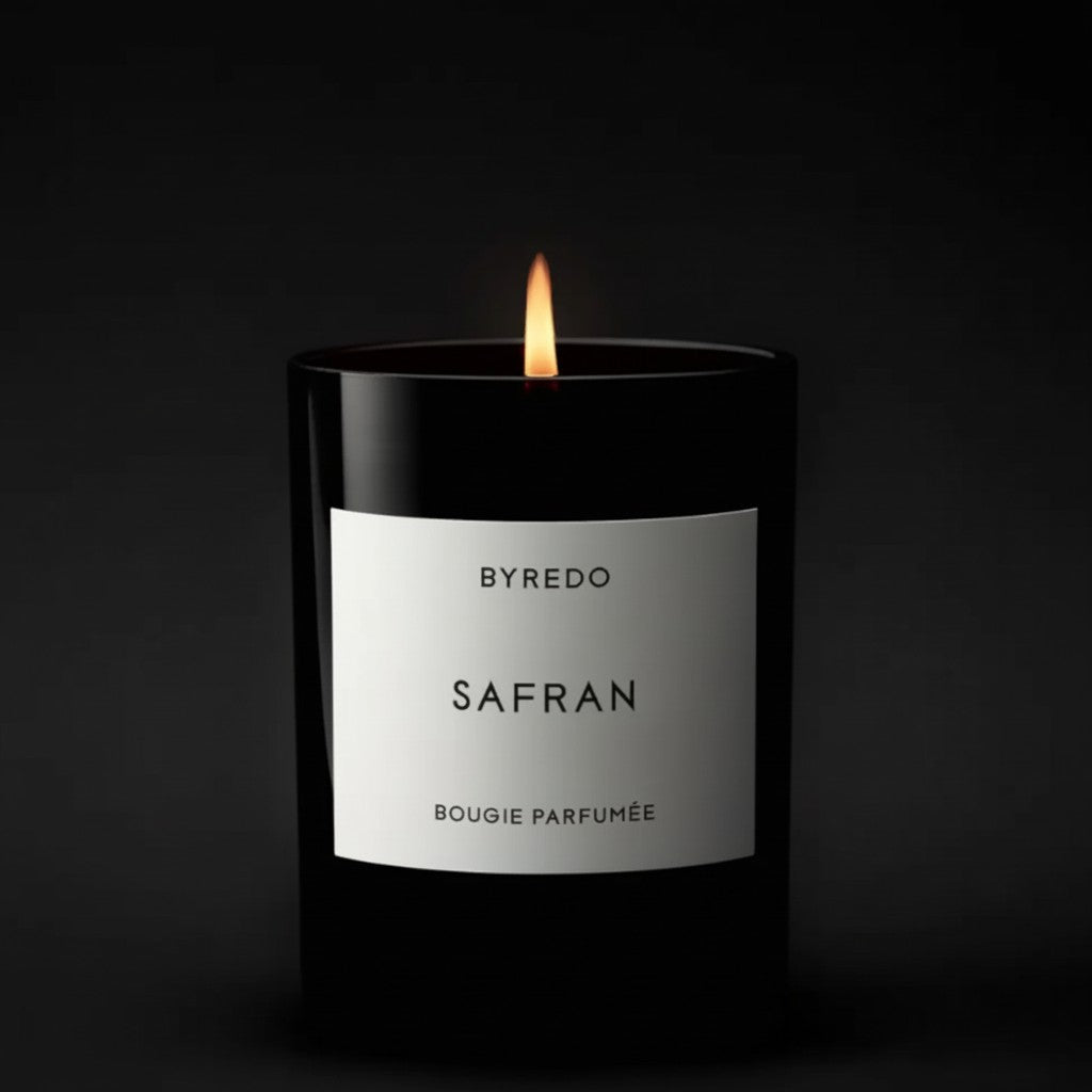Shop Rescue Spa Byredo Safran candle in a black glass vessel with a lit flame. Saffron and spice fragrance.