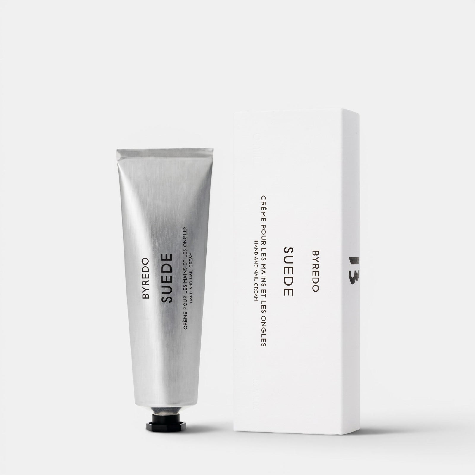 Shop Rescue Spa Byredo Suede hand and nail cream in a silver tube next to its white minimalist product box.