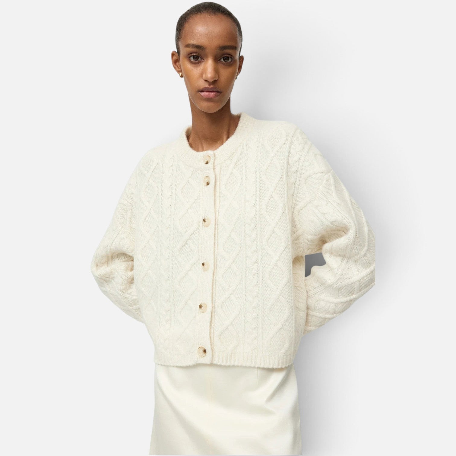Shop Rescue Spa cream cable knit cashmere cardigan with button-up front worn by a model against a white background