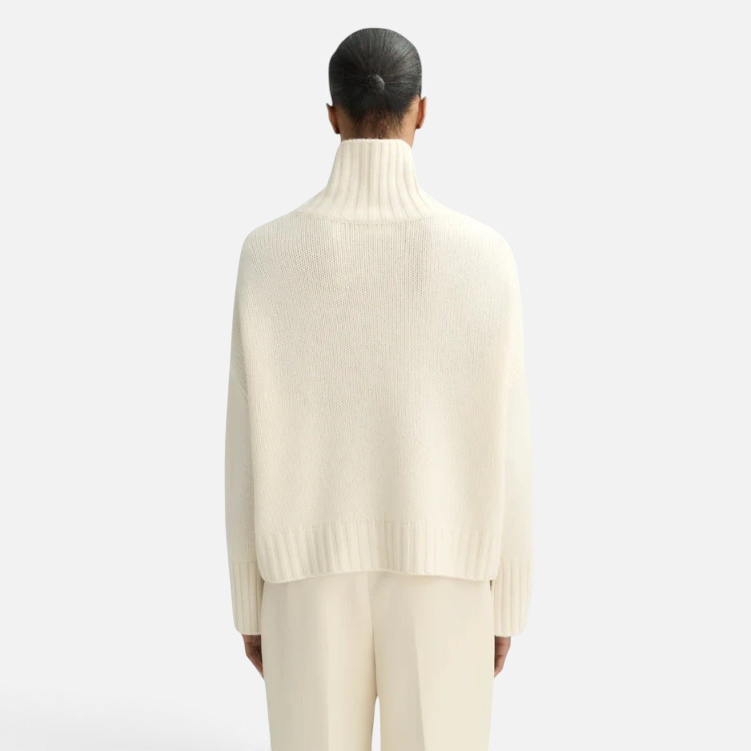 Back view of a model wearing a Shop Rescue Spa chunky cream cashmere turtleneck sweater with a relaxed fit.