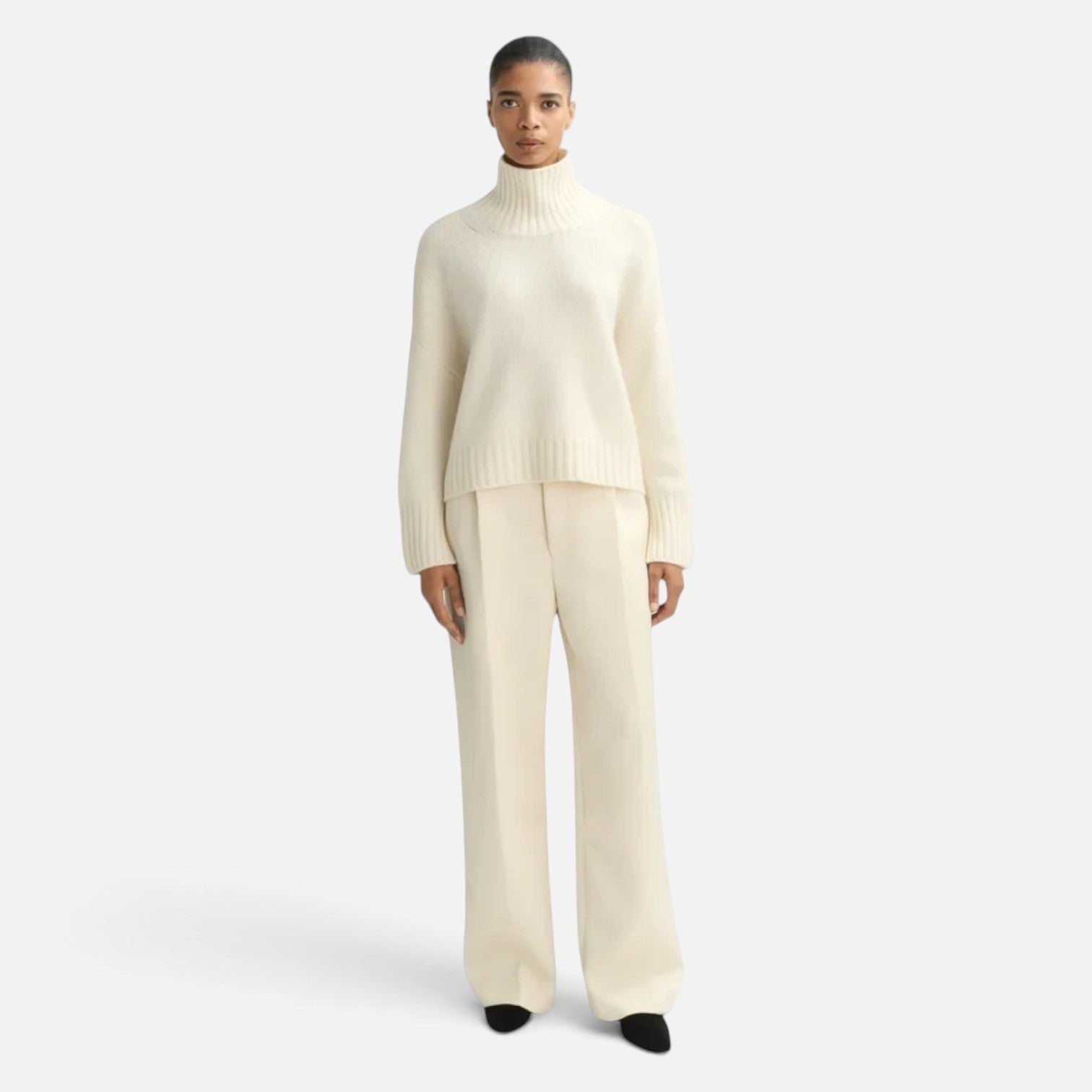 Shop Rescue Spa Girlfriend Turtleneck in cream 100% cashmere with chunky knit and sleeve slits on a model