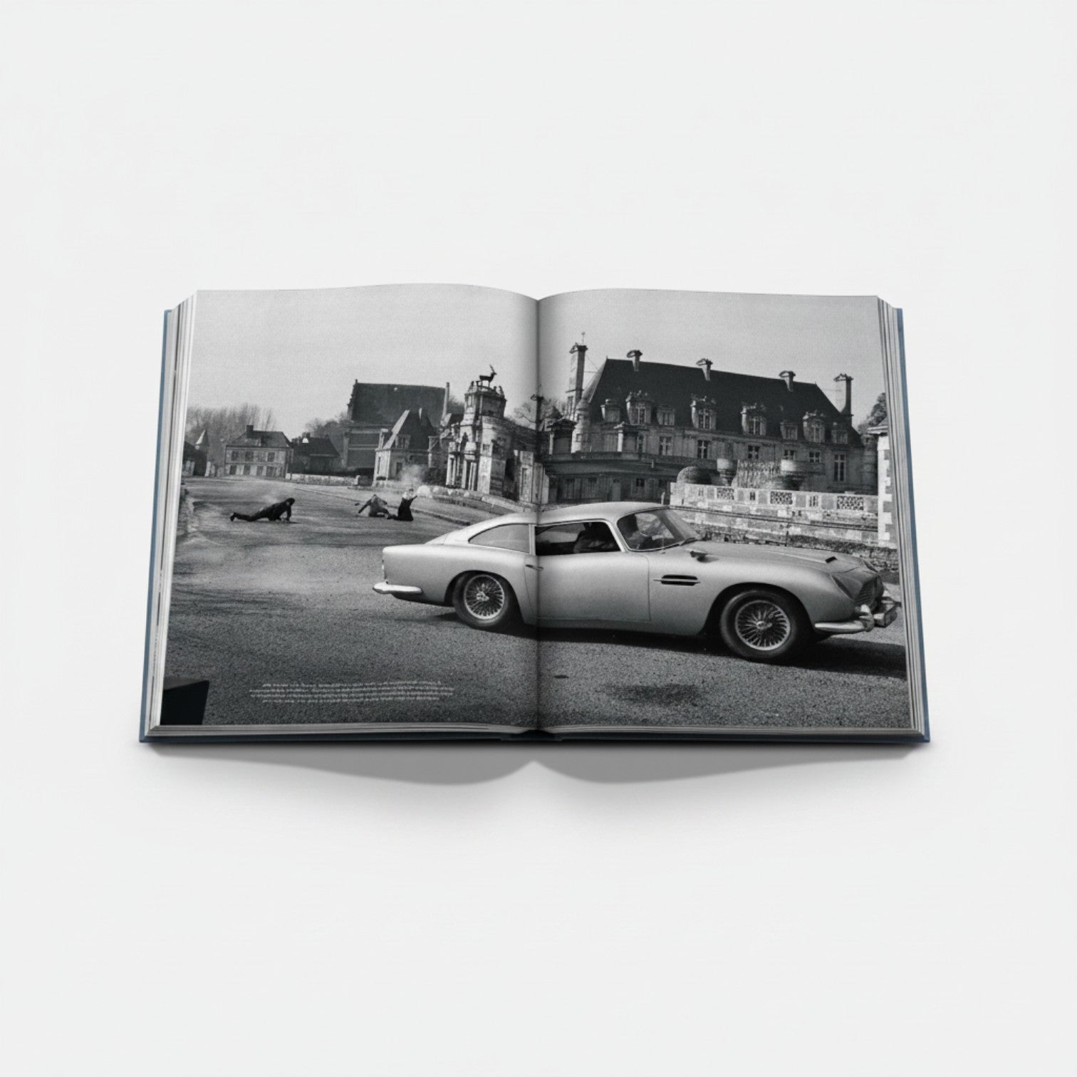 James Bond Cars book featuring an Aston Martin DB5 in a black and white scene with a chateau in the background.