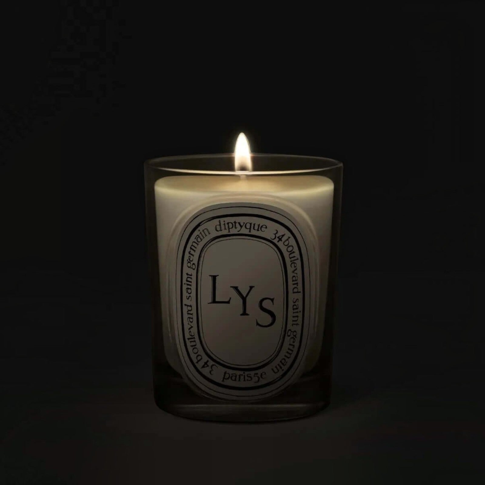 Shop Rescue Spa Lys scented candle in a glass vessel with a glowing flame against a dark background.