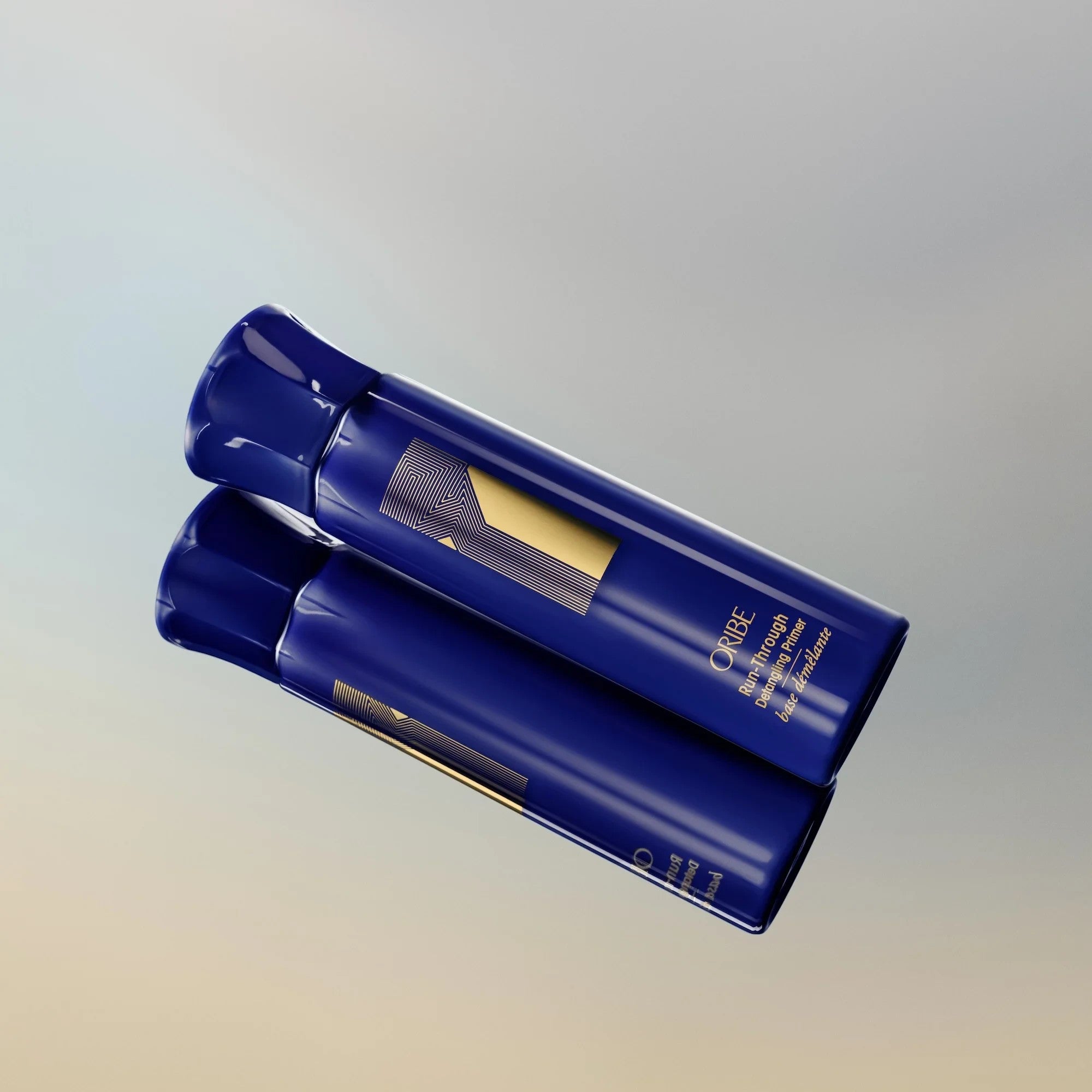 Shop Rescue Spa Oribe Run-Through Detangling Primer in a blue bottle with gold logo on a reflective surface.