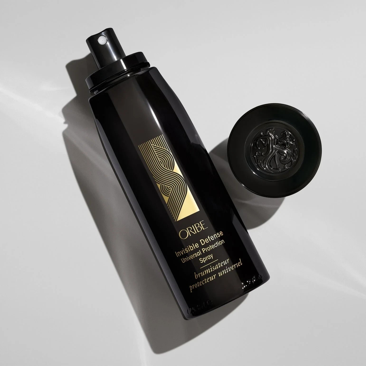Shop Rescue Spa Oribe Invisible Defense Universal Protection Spray in a black bottle with a gold logo on white surface