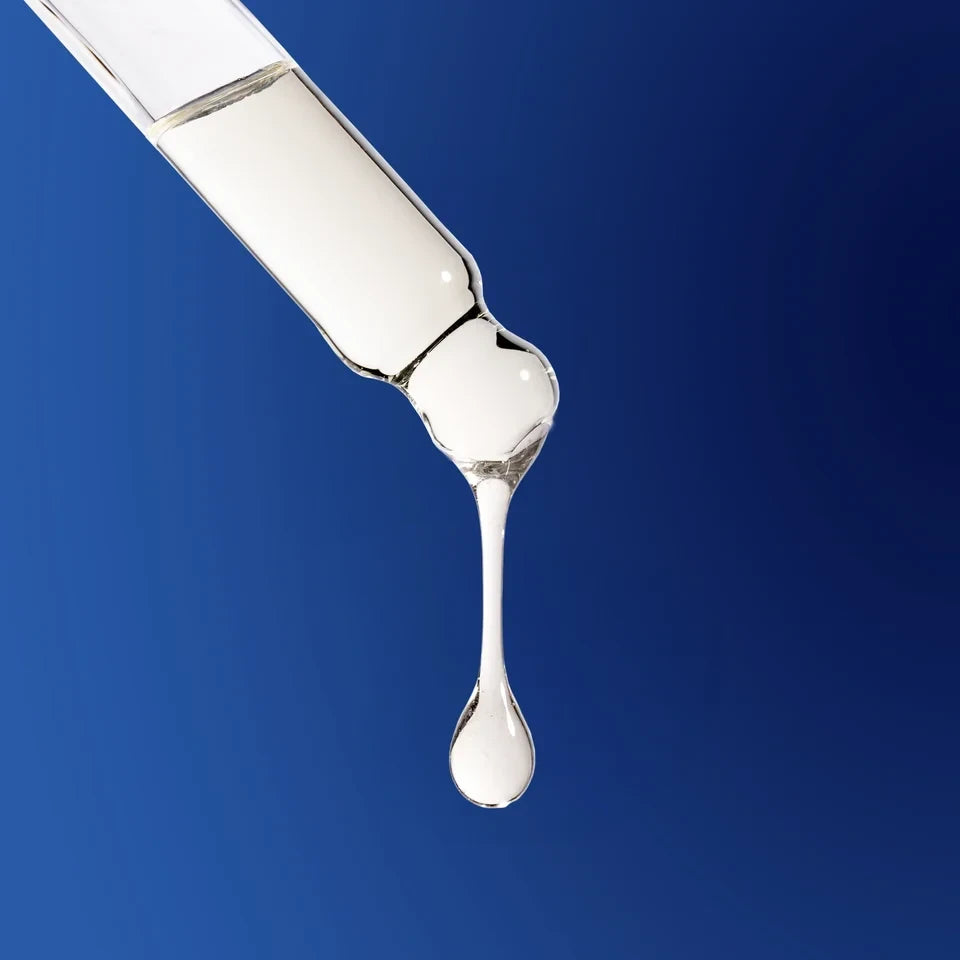 Shop Rescue Spa The Scalp Treatment serum dripping from a glass dropper against a deep blue background