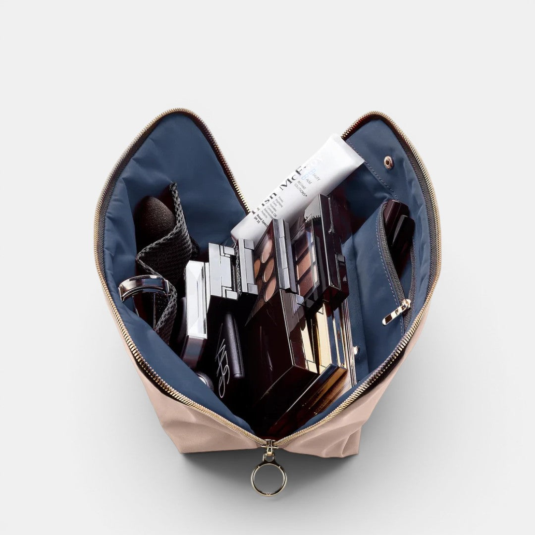 Shop Rescue Spa Signature Leather Makeup Bag in beige with navy interior, holding makeup palettes and a tube of cream.