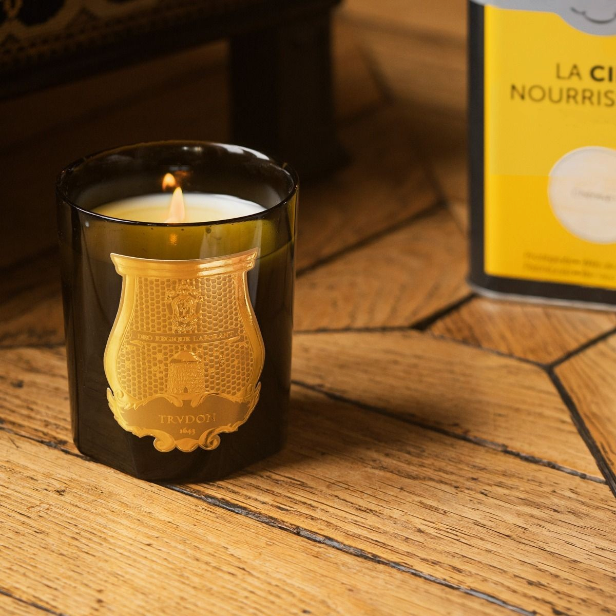 Shop Rescue Spa Solis Rex classic candle in a dark glass vessel with a gold embossed crest on a wooden floor
