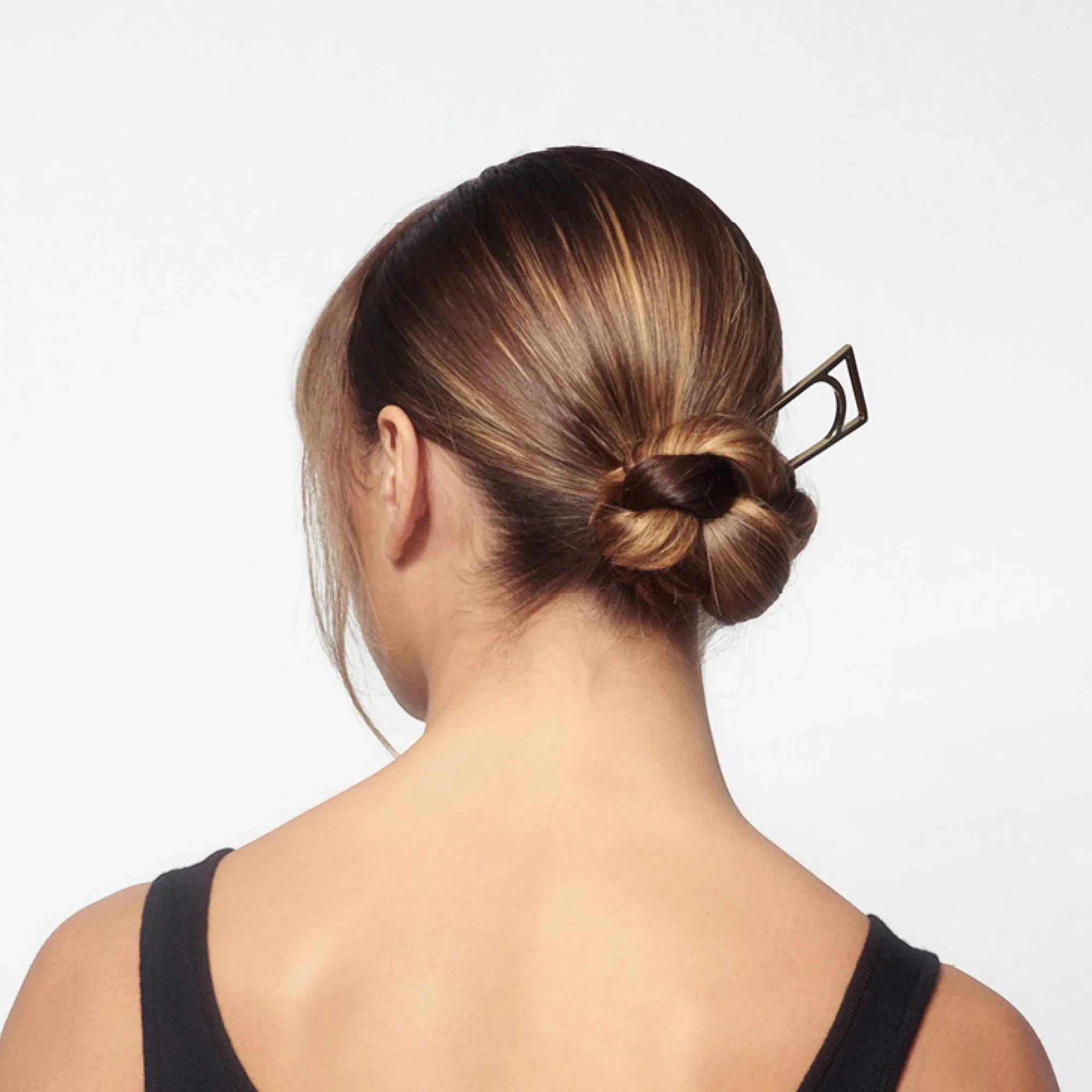 Shop Rescue Spa Superfine Hair Spray used to style a sleek, shiny bun with a geometric hair pin on highlighted hair