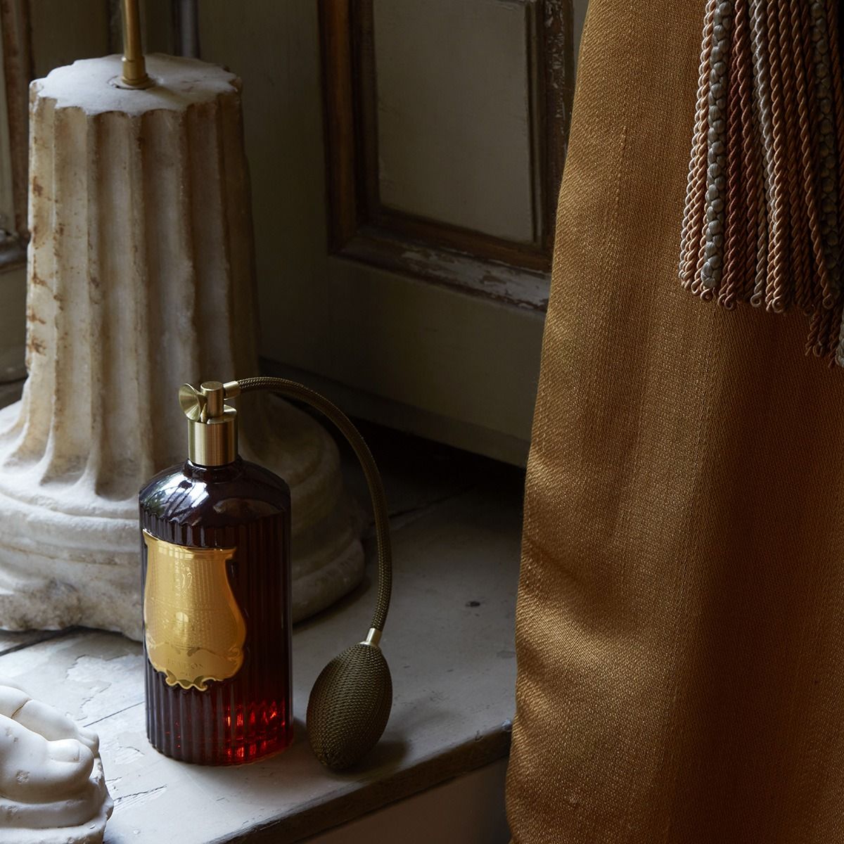 Decorative bottle with gold cap on a surface with architectural elements in the background