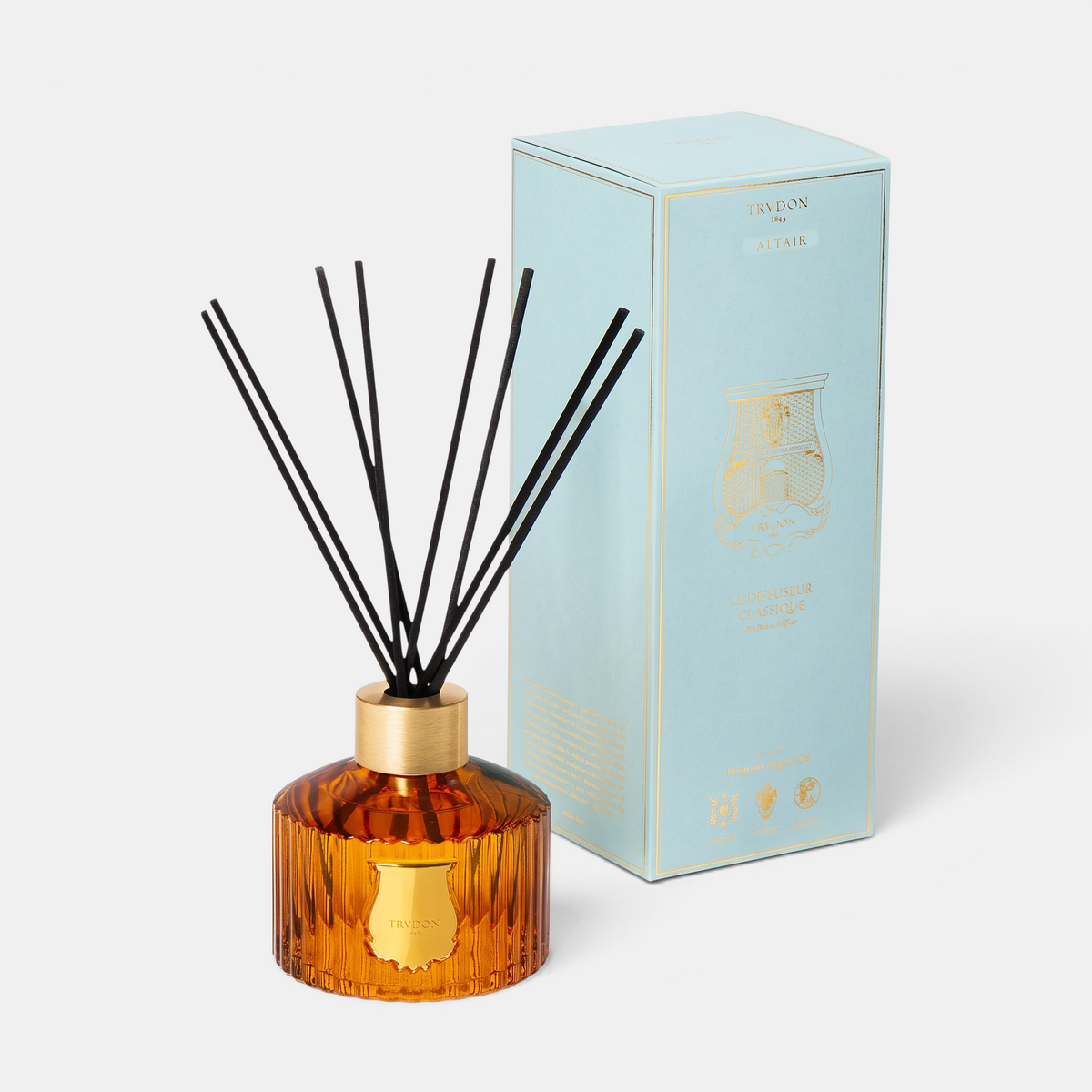 Shop Rescue Spa Le Diffuseur Altair with amber ribbed glass vessel, gold emblem, and black reeds beside light blue box