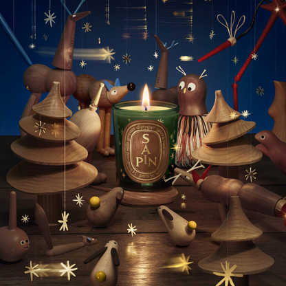 Shop Rescue Spa Diptyque Sapin candle in a green glass jar surrounded by whimsical wooden forest animal figurines