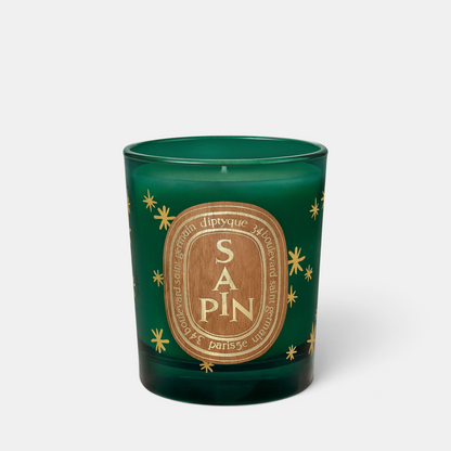 Shop Rescue Spa Diptyque Sapin holiday candle in a green glass jar with gold star accents and wooden label detail