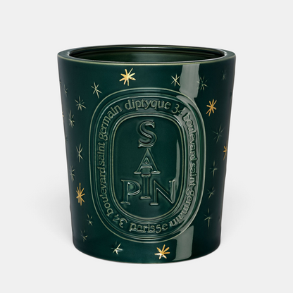 Shop Rescue Spa Diptyque Sapin holiday candle in a dark green glass jar with gold star accents and embossed lettering.