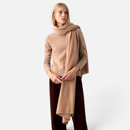Shop Rescue Spa beige cashmere travel wrap worn as a scarf by a woman in a matching sweater and dark trousers