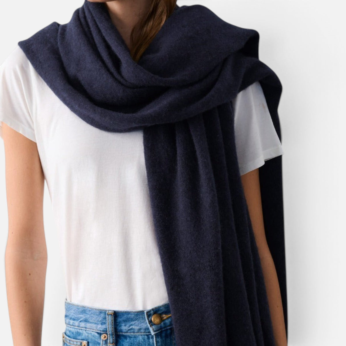 Shop Rescue Spa navy blue cashmere travel wrap draped over a model wearing a white t-shirt and blue jeans
