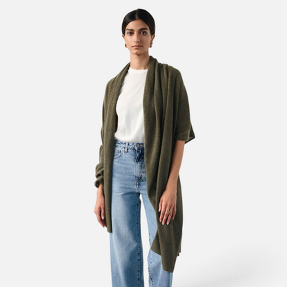Shop Rescue Spa olive green cashmere travel wrap worn by a model over a white t-shirt and blue jeans