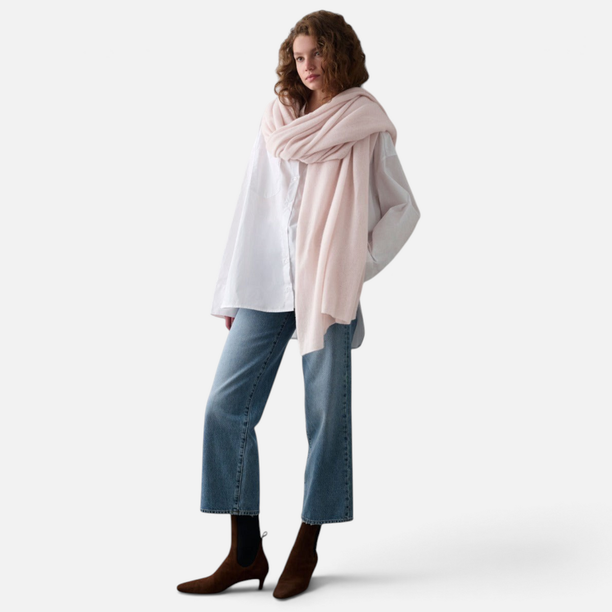 Shop Rescue Spa soft pale pink cashmere travel wrap worn over a white shirt and blue jeans by a woman