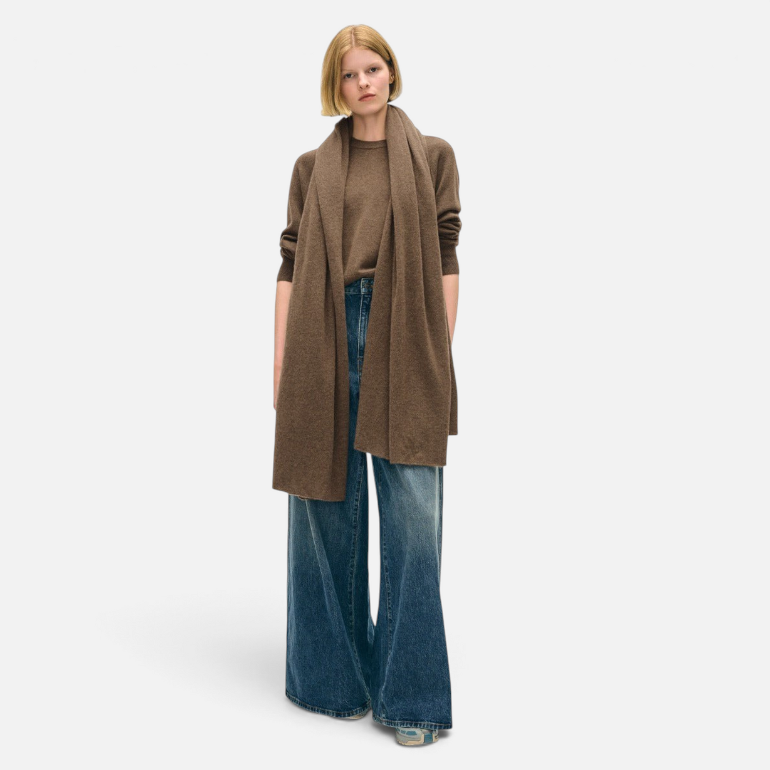 Shop Rescue Spa brown cashmere travel wrap worn as a scarf by a model in a matching sweater and wide-leg jeans