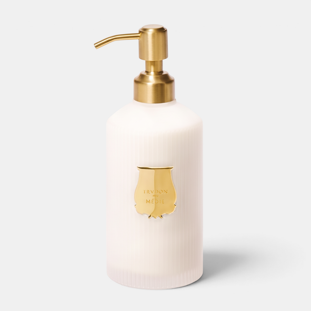 Shop Rescue Spa Trudon Médie scented hand lotion in a white ribbed bottle with a gold pump and signature gold emblem.