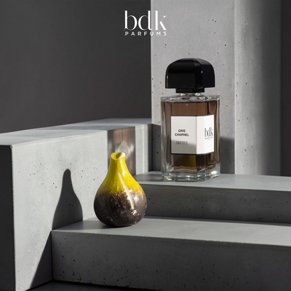 Shop Rescue Spa BDK Parfums Gris Charnel 100ml perfume bottle on a grey concrete display with a decorative fig object