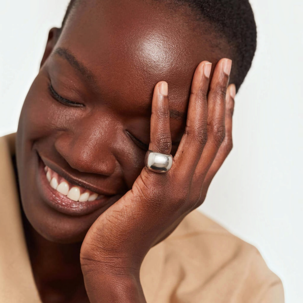 Shop Rescue Spa Tate Signet Ring in high-polish platinum-plated steel worn on a finger by a smiling model