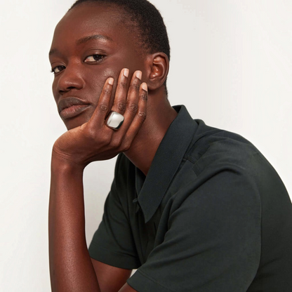 Model wearing a Shop Rescue Spa Tate Ring in platinum-plated steel with a bold, rounded rectangular silhouette.