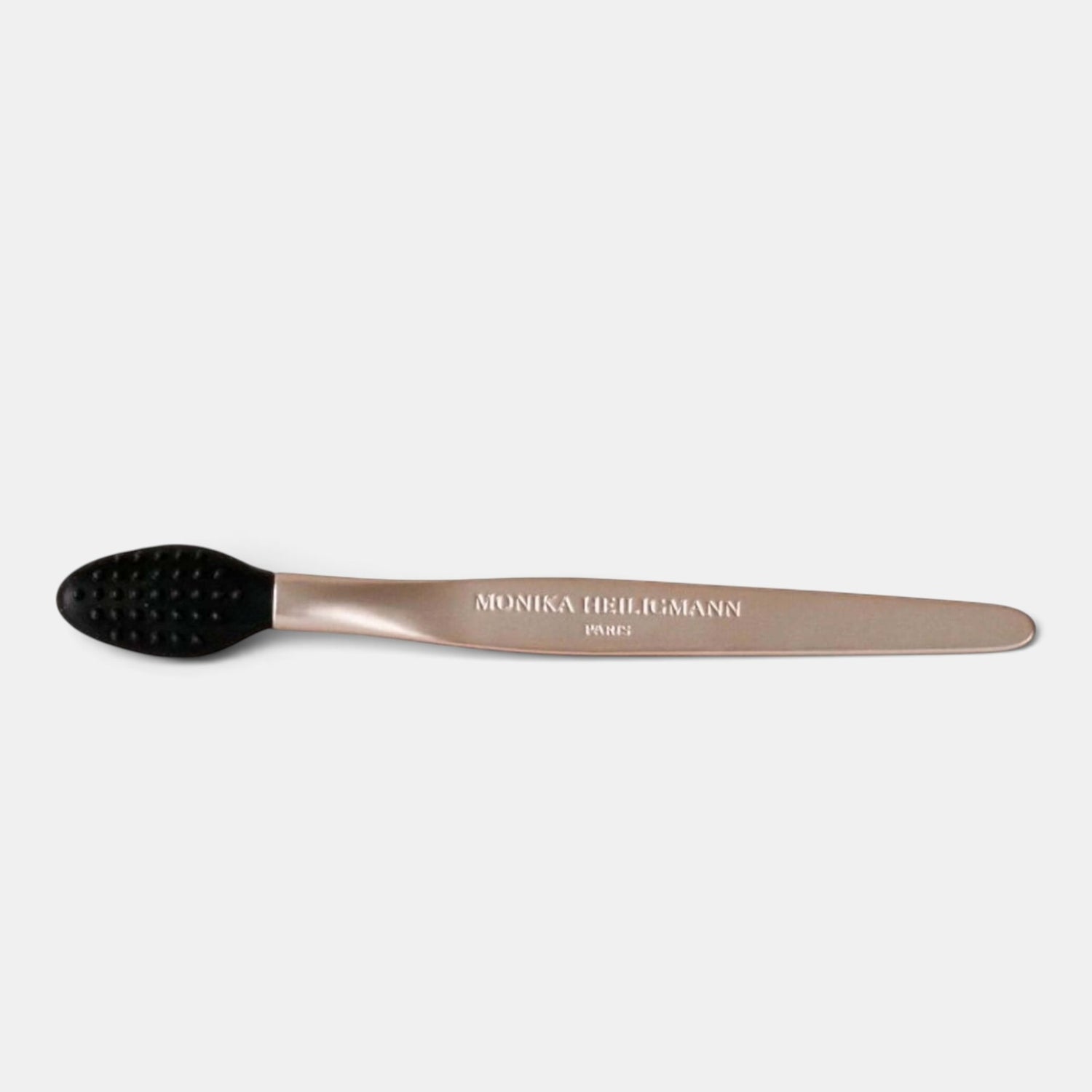 A metallic rose gold massage tool with a black silicone head, featuring the brand name &