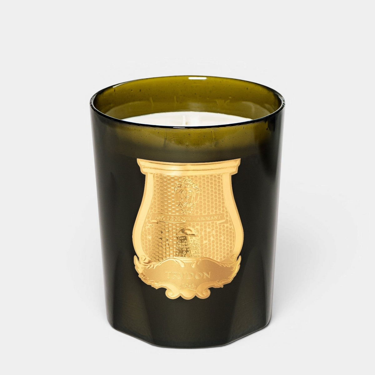 Shop Rescue Spa Trudon Ernesto scented candle in a dark green glass vessel with a gold emblem on a white background.