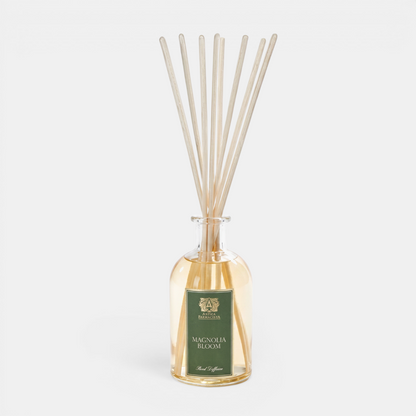 Antica Magnolia Bloom reed diffuser with wooden sticks in a glass bottle on a white background