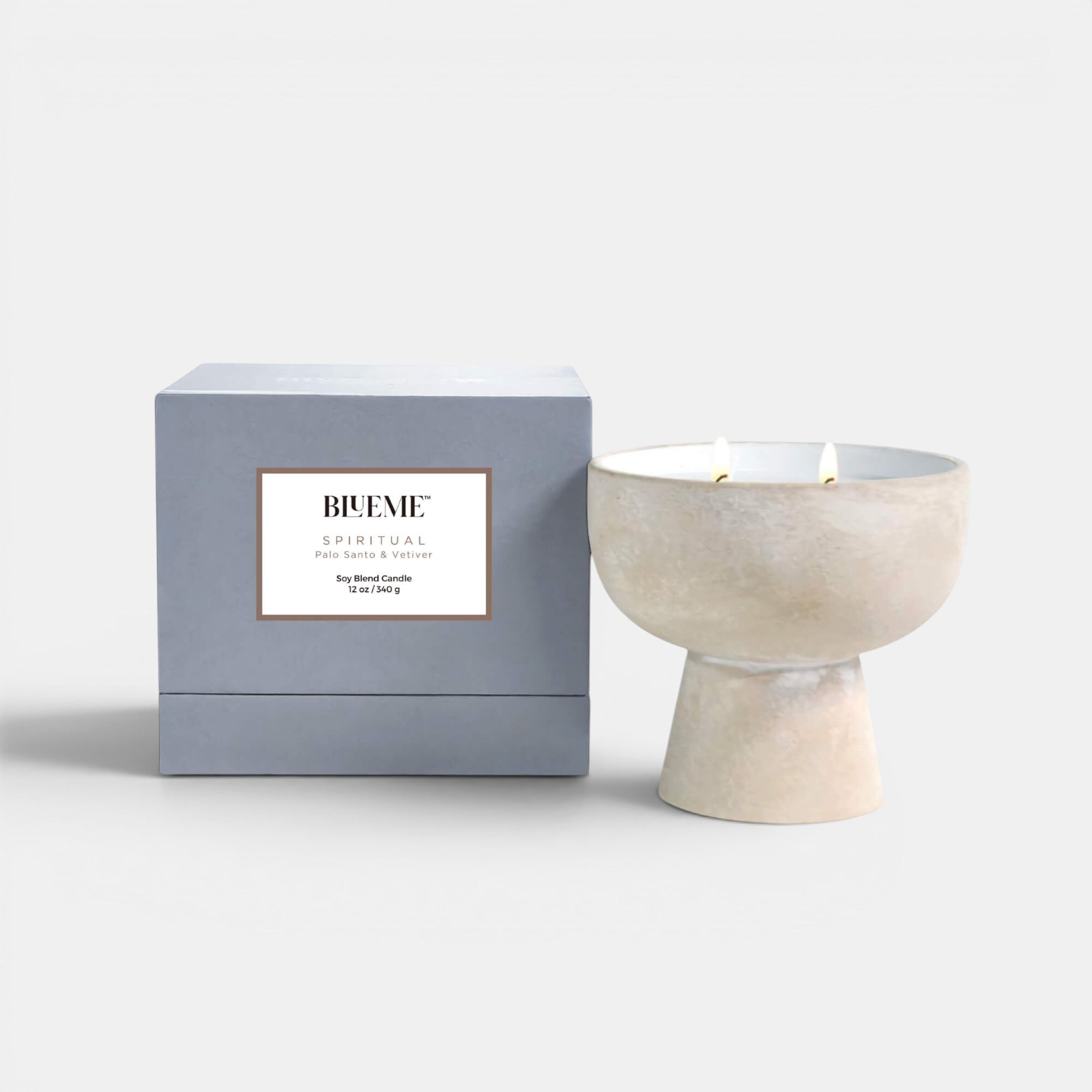 Blueme Fragrance spiritual ceramic candle positioned upright showing the lit candle and the box. Palo Santo and Vetiver scented candle.