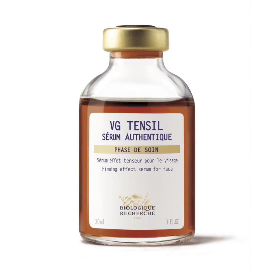 Biologique Recherche VG Tensil Sérum Authentique 1.0 fl. oz – clear glass bottle with a gold cap, filled with a brown liquid. The bottle features a branded white label with blue lettering, photographed against a clean white background.