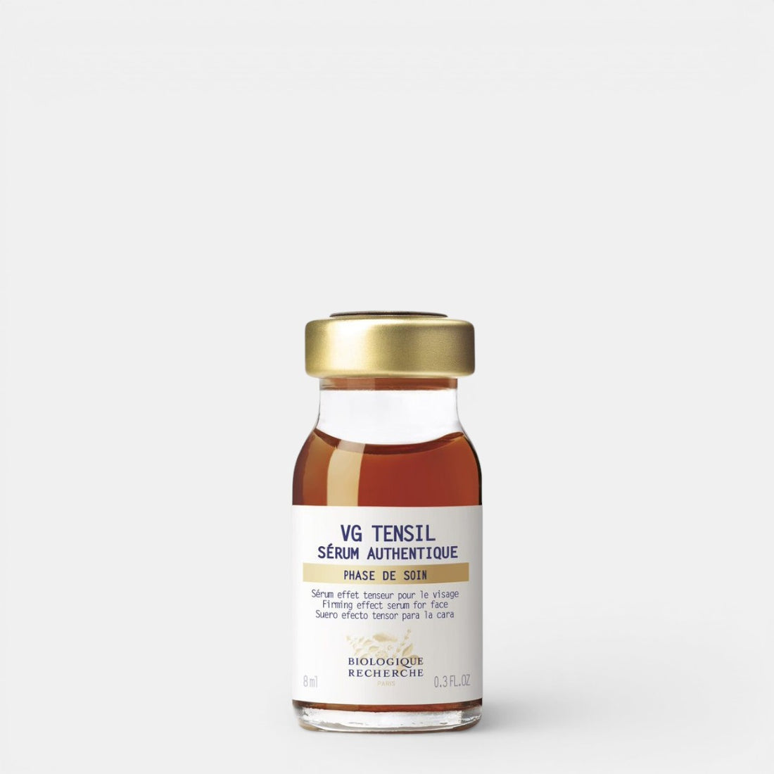 VG Tensil Sérum Authentique 0.3 fl. oz – A clear glass bottle filled with brown liquid, topped with a gold cap. The product features a branded white label with blue lettering, photographed against a clean white background. This smaller size of the firming botanical serum by Biologique Recherche is ideal for travel or targeted skincare routines.