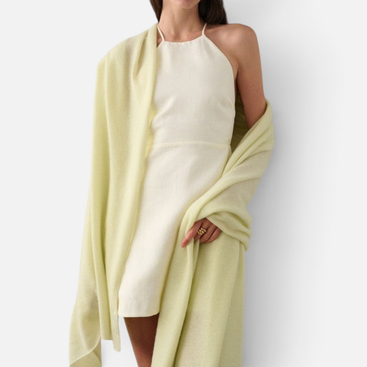 Shop Rescue Spa pale yellow cashmere travel wrap draped over a woman wearing a white mini dress