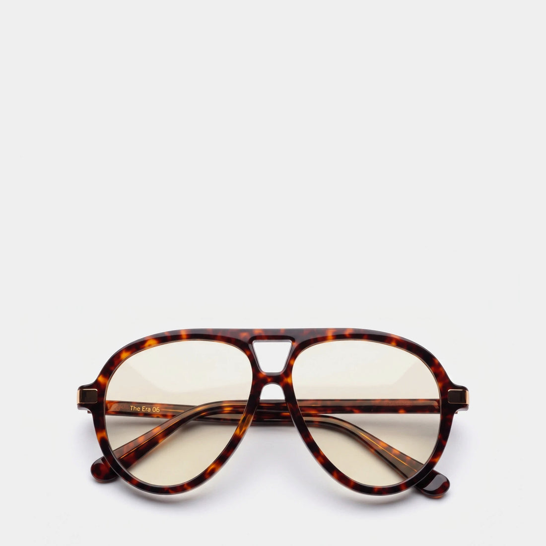 A pair of aviator-style eyeglasses with a classic tortoiseshell acetate frame and clear lenses, displayed on a clean, light gray background.