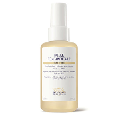A clear glass bottle of Biologique Recherche Huile Fondamentale with a golden botanical oil inside, featuring a white label and gold cap, photographed on a clean white background.
