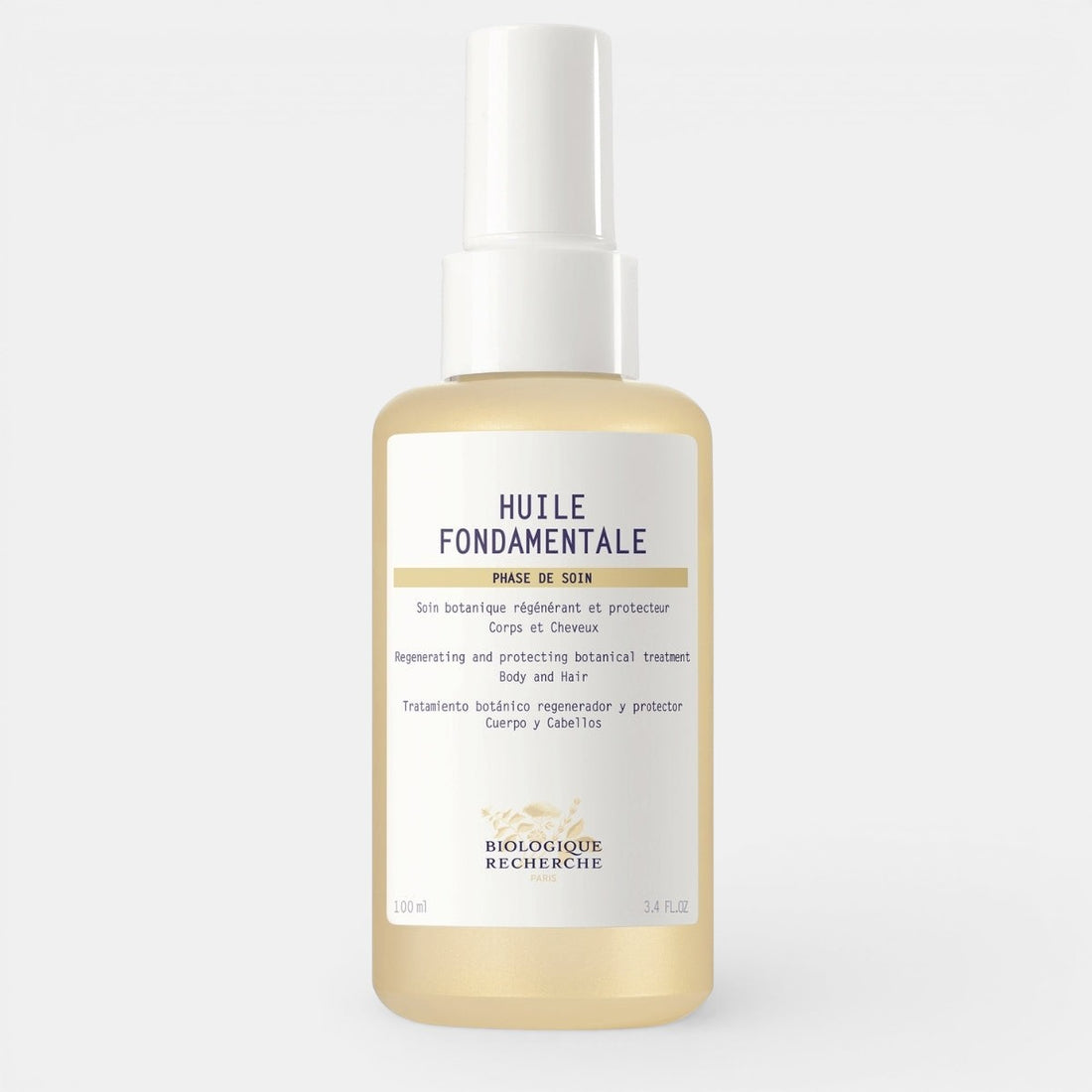 A clear glass bottle of Biologique Recherche Huile Fondamentale with a golden botanical oil inside, featuring a white label and gold cap, photographed on a clean white background.