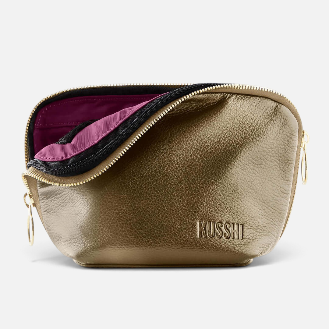 Shop Rescue Spa metallic gold leather makeup bag with a zip-out purple interior liner and gold zipper hardware.