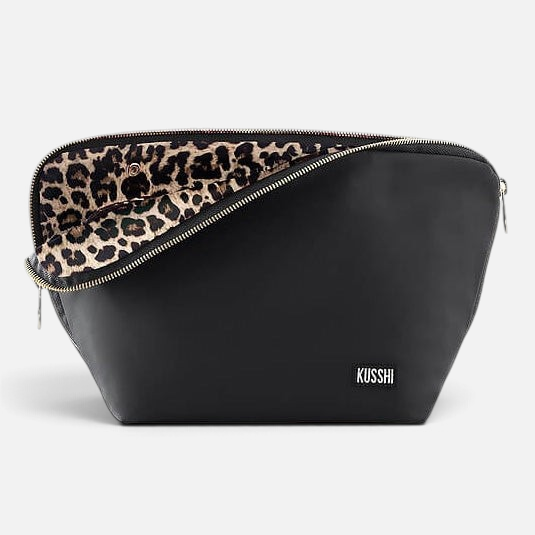 Shop Rescue Spa Vacationer makeup bag in black leather with a leopard print interior and three-sided zipper opening.