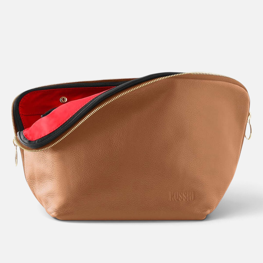 Shop Rescue Spa Vacationer makeup bag in tan leather with a vibrant red interior and gold zipper detail.