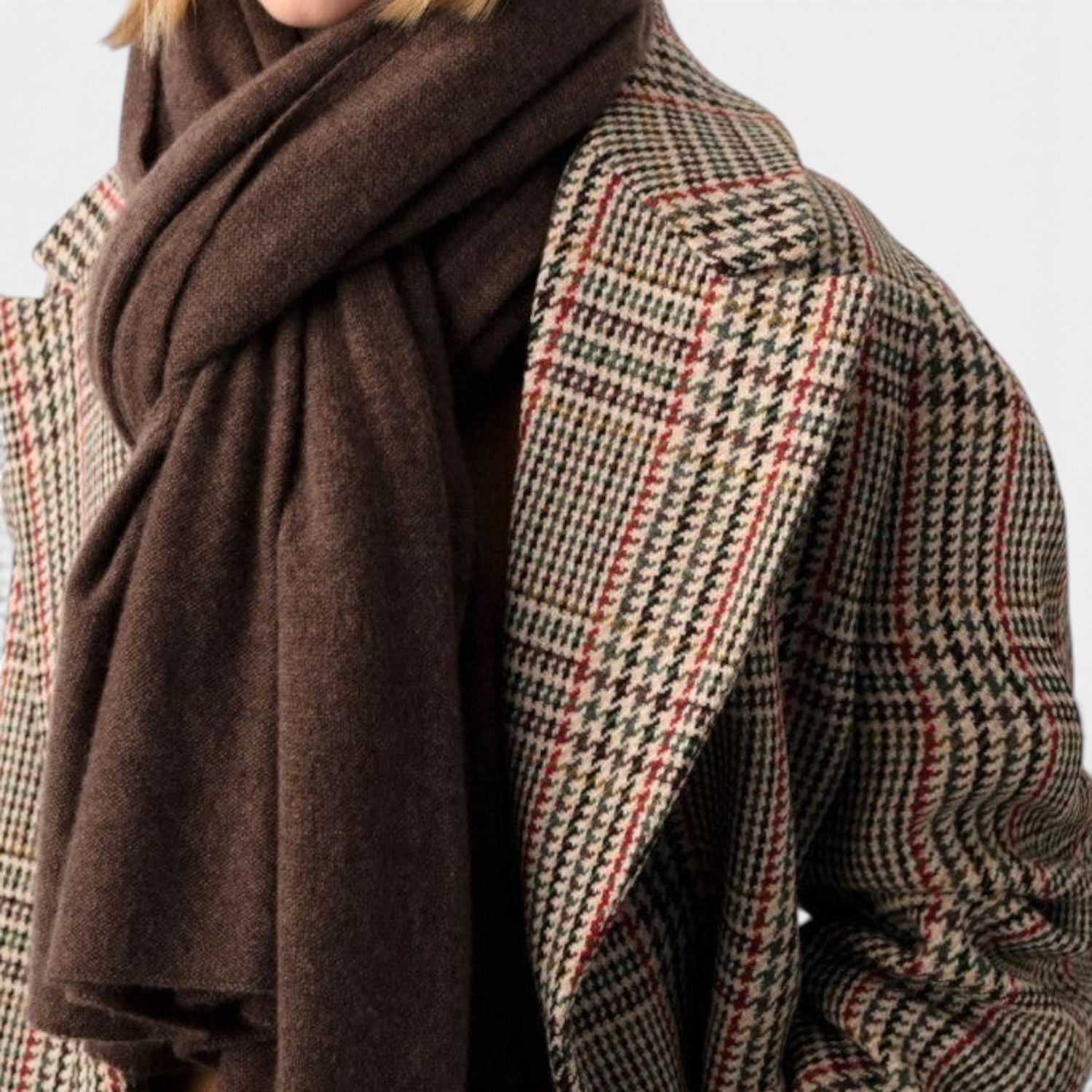 Shop Rescue Spa dark brown cashmere travel wrap worn over a plaid wool coat by a blonde model.