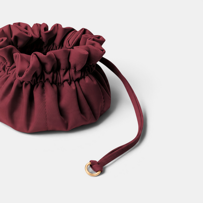 Shop Rescue Spa Lotus Petit jewelry pouch in deep burgundy neoprene with a drawstring closure and brushed gold ring.